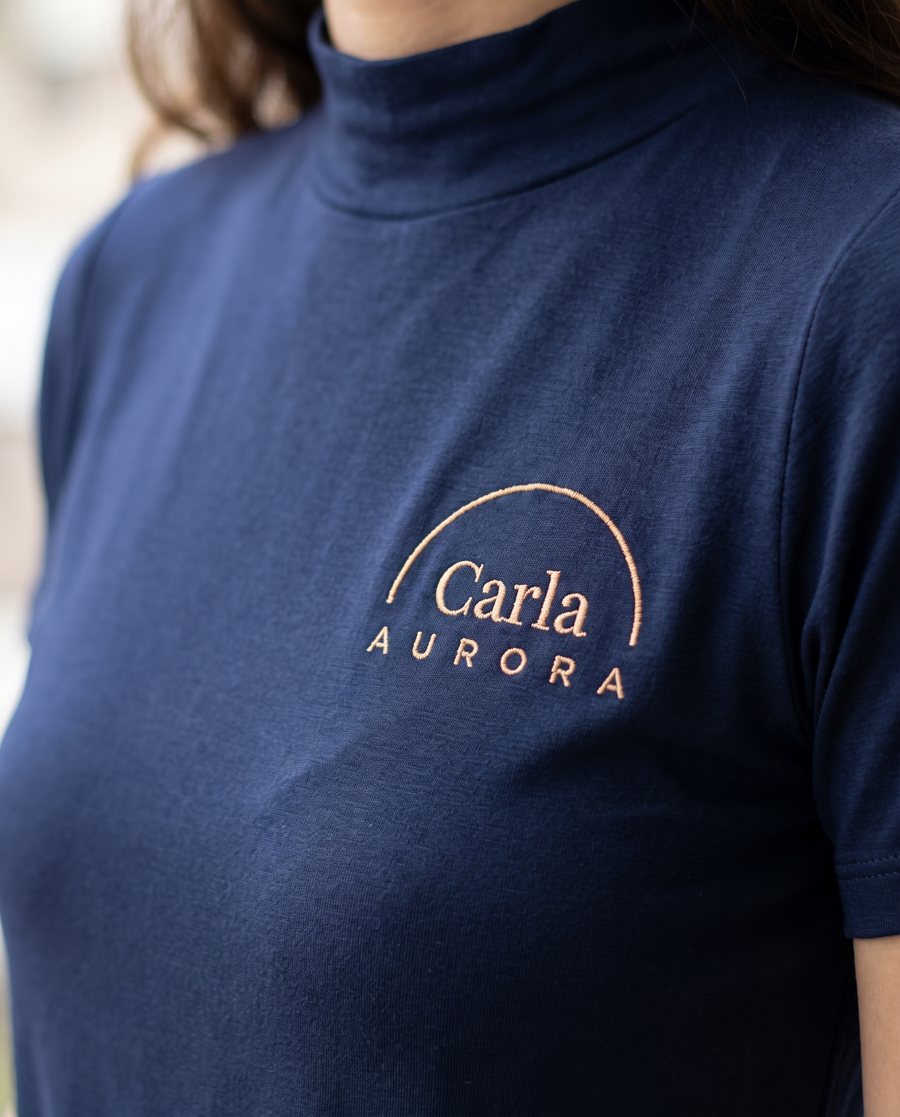 Camiseta azul-marinho com o nome Carla e o logo Aurora bordados no peito